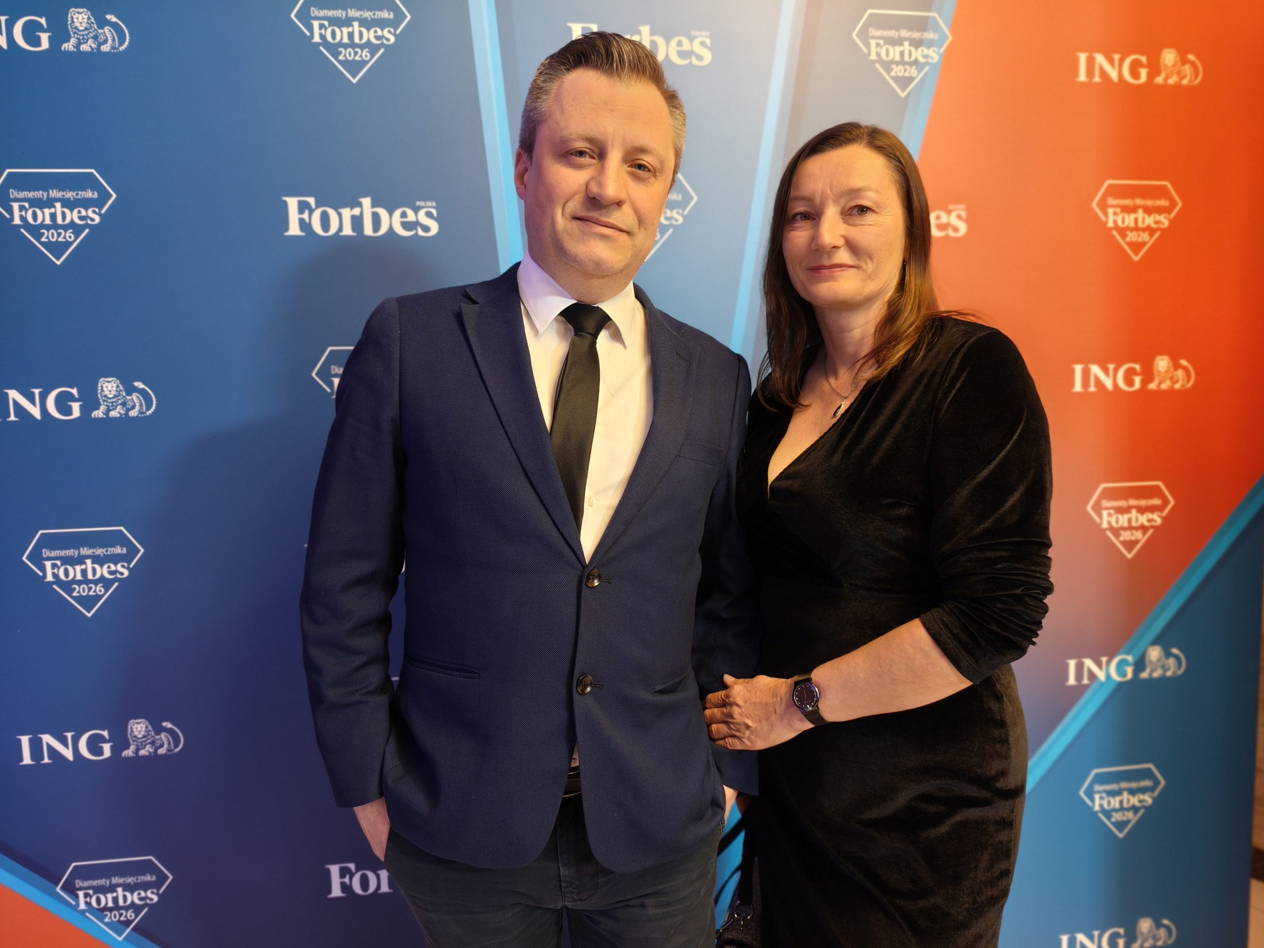 Kobieta i mężczyzna na tle ścianki do zdjęć.