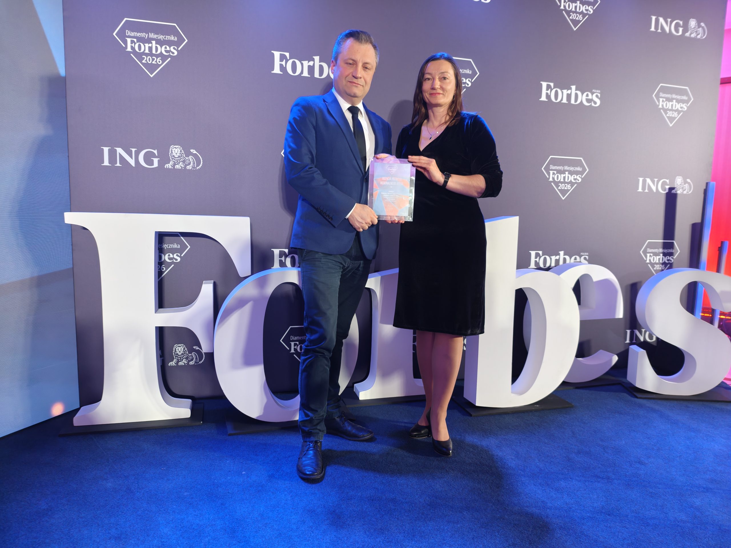 Reprezentacja firmy pozuje do zdjęcia z dyplomem w rękach.