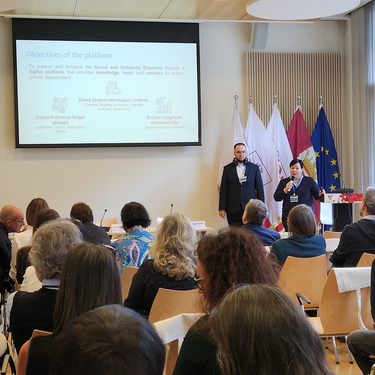 Widownia konferencji w tle prelegentka z mikrofonem